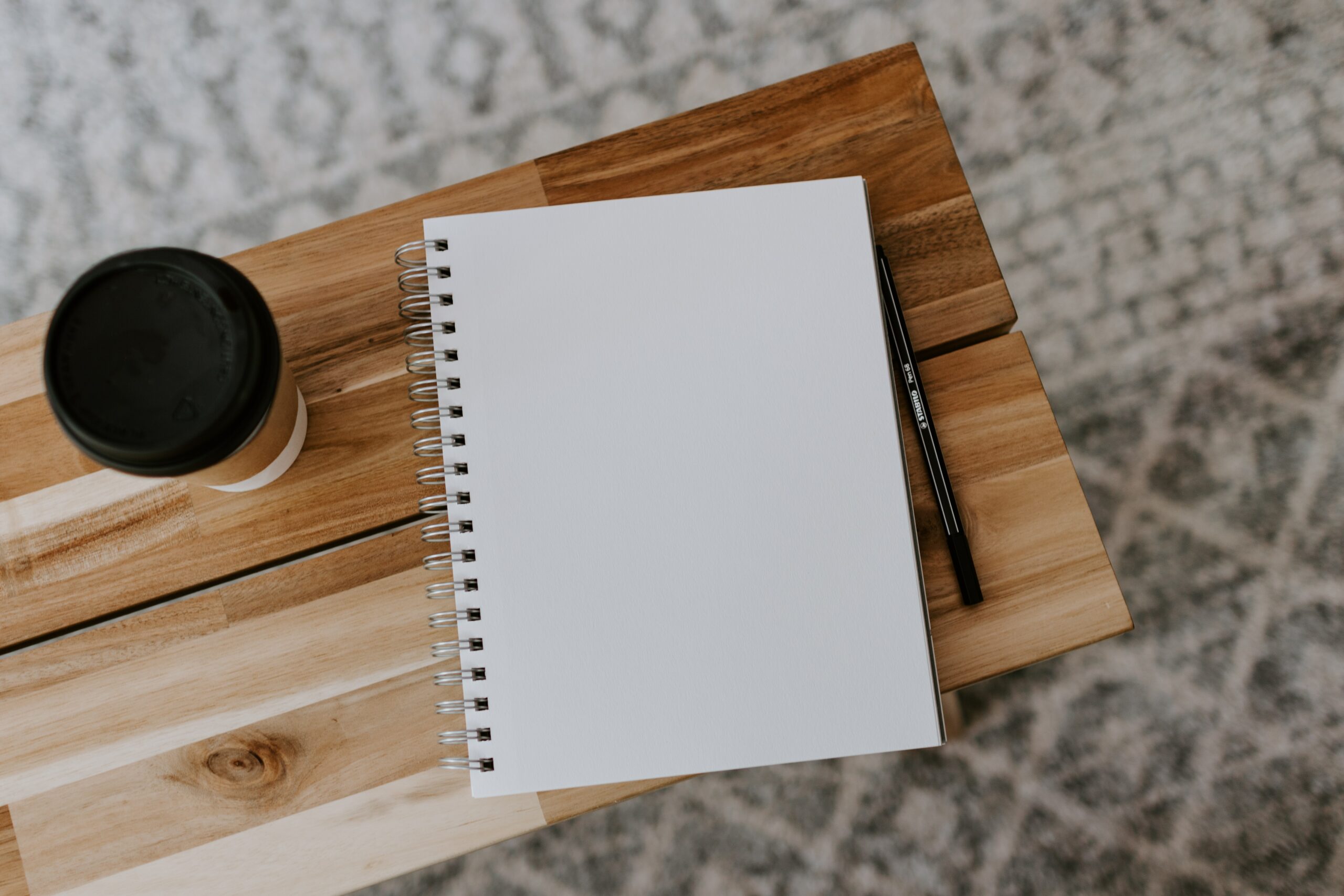 carnet vierge, stylo et gobelet de café sur un tabouret en bois